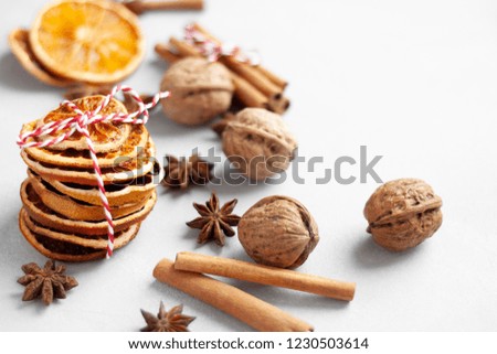 Closeup view of winter flavouring ingredients: dry orange slices, cinnamon, anise stars, walnuts, empty space on the right side of the picture.