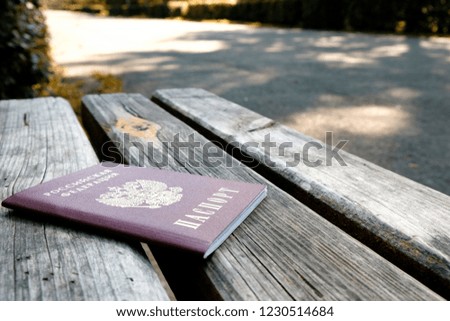 Russian passport on a wooden bench on a summer day, the background of the paved path in the Park