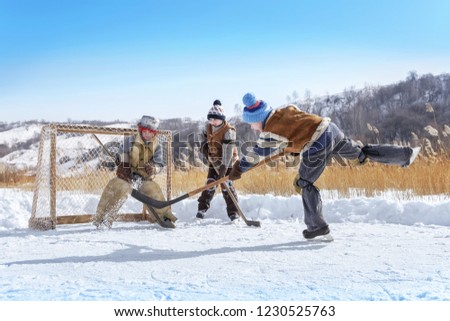Boys play hockey on a frozen lake on a winter sunny day