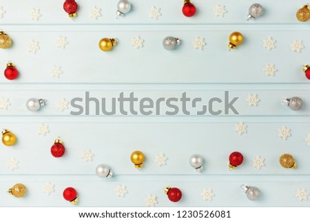 Copy space on light blue background. Christmas frame made of silver, gold and red balls and decorative snowflakes. Holiday layout with space for text.