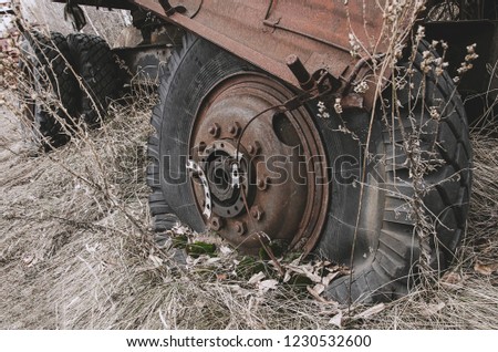 a broken wheel of abandoned construction equipment, covered with grass and moss, a pale picture from the world of the apocalypse