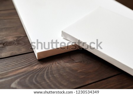 Two white blank canvases on brown wooden background. Mockup