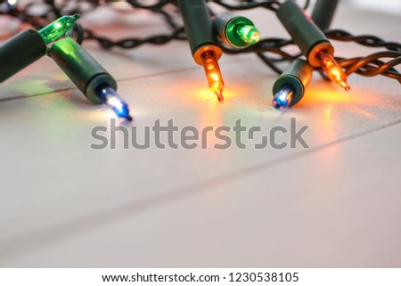 Wooden table with glowing Christmas lights, closeup