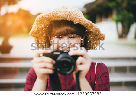 Young female photographer holding professional camera on street.