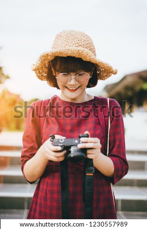 Young female photographer holding professional camera on street.