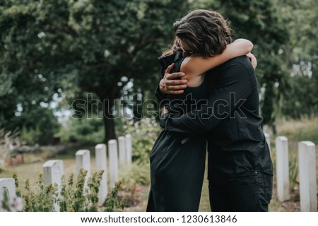 Husband trying to comfort his wife at a graveyard Royalty-Free Stock Photo #1230613846