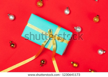 Christmas background with golden decorations and gift present box put as frame on red background. Bright and festive flat lay. Top view. Greetings for christmas or new year. Minimalist picture