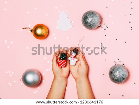 Child's hands holding big snow flake in hands on sparkling pink background. Bright and festive Christmas and New Year picture. Top view, flat lay.