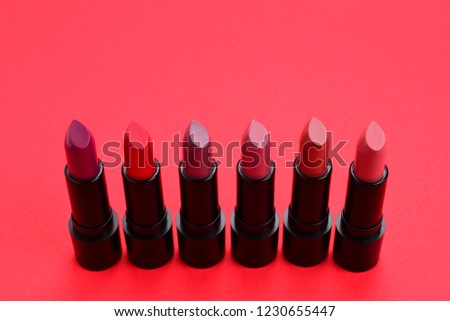 Many different lipsticks, different colors on lilac background. Space for text or design.
