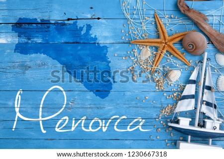 Maritime decoraton on blue wood with shells, starfish, sailship and gravel with graphic isle Menorca