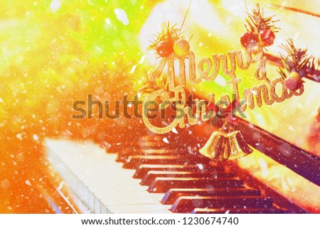 word Merry Christmas hanging over piano keys  near Christmas tree decoration with light effected, Snowy fall covered  with copy space