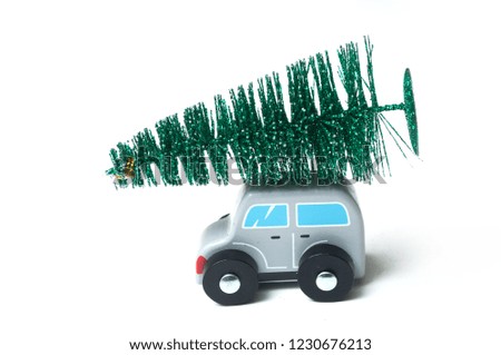 closeup of grey miniature wooden car with christmas tree on the roof on white background