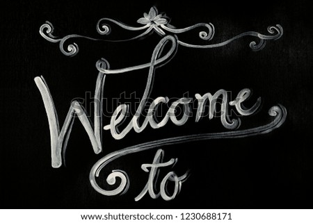 Welcome written on chalkboard with black plant, Top View Selective Focus.
