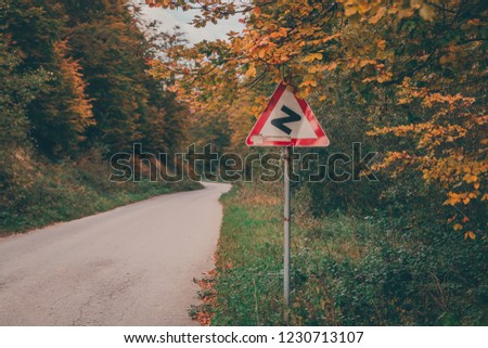 Roadway and yellow and green winding road sign in Serbia