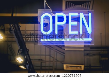 Neon light color blue Open sign on a glass window for business front of shop.