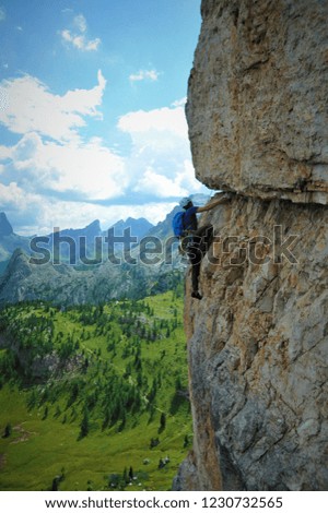 A climber (male) high up on a mountain, with a stunning mountain  view in the background. Picture from the Dolomites, Italy.