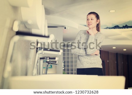 Positive woman customer choosing  wash basin in bathroom fitment store