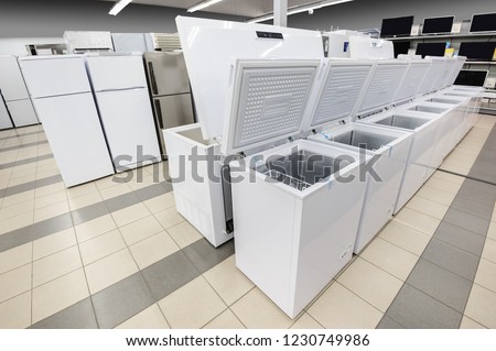 Rows of white top loading freezers and fridges in appliance store's showroom Royalty-Free Stock Photo #1230749986