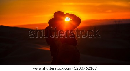 Man taking a picture of the sunset and sand dunes