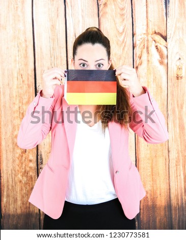 Young business woman hiding behind the flag of Germany against a wooden background