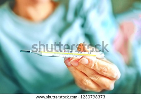 Thermometer in the hand close-up. Ill woman shows a thermometer in the hand with the result of body temperature