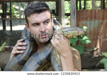 Powerful man struggling with gigantic anaconda