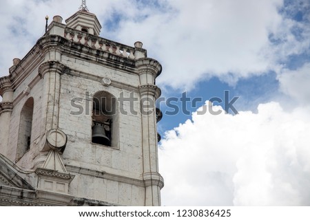 Old catholic church. White stone bell tower on blue sky background. Basilica de Santo Nino in Cebu, the Philippines. Historical landmark. Spanish style catholic cathedral tower with white clouds