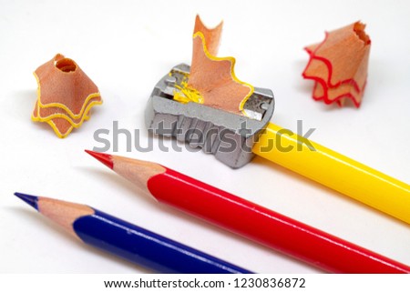 Color pencil and prism sharpener macro photo on white background. Drawing as hobby banner template. Sharpening pencils concept. Yellow, red and blue crayons closeup. Children art class creative hobby