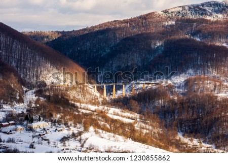 winter rail road transportation in mountains. station and village on hill and viaduct in the distance. beautiful scenery in dappled light