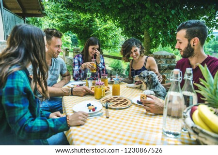 Group of happy people doing breakfast outdoors in a  traditional countryside - Friends eating snacks in the garden