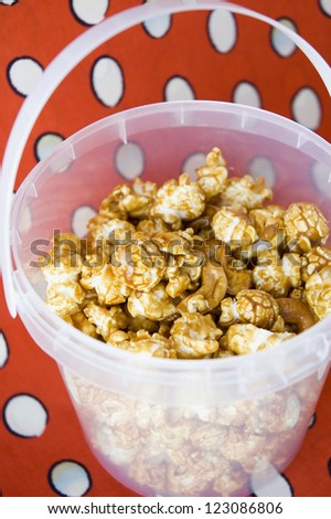 close up caramel popcorn in bucket with red background