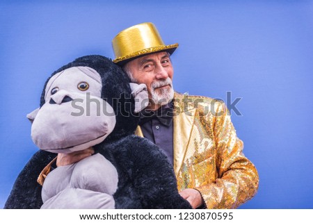 Funny and extravagant senior man posing on colored background - Youthful old man in the sixties having fun and partying Royalty-Free Stock Photo #1230870595