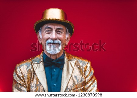 Funny and extravagant senior man posing on colored background - Youthful old man in the sixties having fun and partying Royalty-Free Stock Photo #1230870598