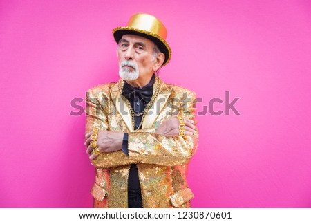 Funny and extravagant senior man posing on colored background - Youthful old man in the sixties having fun and partying Royalty-Free Stock Photo #1230870601