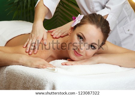 beautiful young woman in spa salon getting massage, on green background