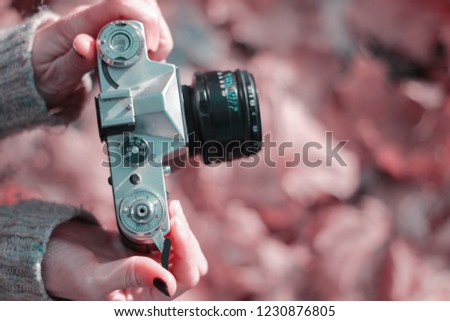 Vintage camera in hand on blurred background. Close-up, focus on camera controls