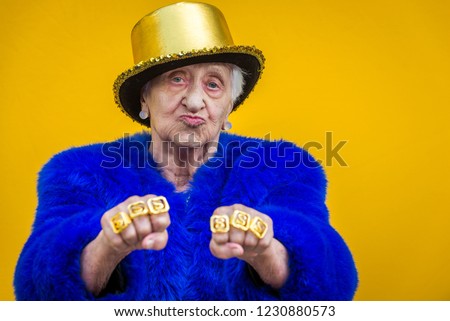 Funny and extravagant senior woman posing on colored background - Youthful old woman in the sixties having fun and partying Royalty-Free Stock Photo #1230880573