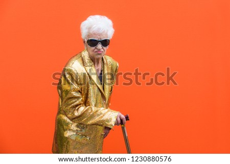Funny and extravagant senior woman posing on colored background - Youthful old woman in the sixties having fun and partying Royalty-Free Stock Photo #1230880576