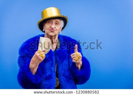 Funny and extravagant senior woman posing on colored background - Youthful old woman in the sixties having fun and partying Royalty-Free Stock Photo #1230880582
