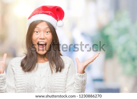 Young asian woman wearing christmas hat over isolated background celebrating crazy and amazed for success with arms raised and open eyes screaming excited. Winner concept