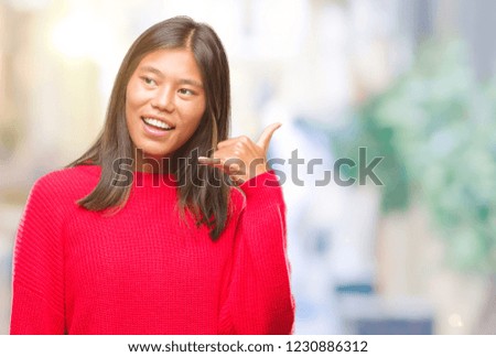 Young asian woman wearing winter sweater over isolated background smiling doing phone gesture with hand and fingers like talking on the telephone. Communicating concepts.