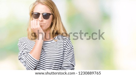 Beautiful young woman wearing sunglasses over isolated background looking stressed and nervous with hands on mouth biting nails. Anxiety problem.