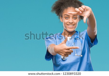 Young afro american doctor woman over isolated background smiling making frame with hands and fingers with happy face. Creativity and photography concept.