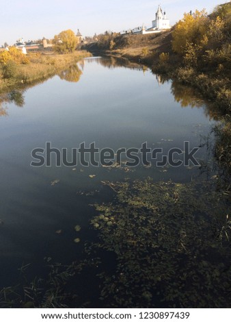Suzdal. Russia. Golden autumn. View of the river with the church. Fallen leaves and duckweed on the water.
