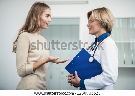 Concept of professional inspiration in healthcare system. Waist up portrait of cheerful female doctor discussing something with young woman in medical office