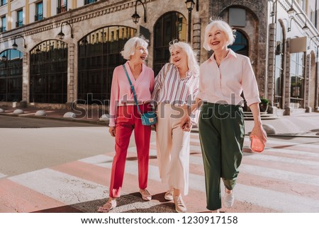Full-length photo of happy older women are walking in center of city while having fun Royalty-Free Stock Photo #1230917158