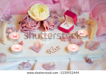 Valentine's Day Surprise.Romantic evening with the beloved with rose petals on the bed and a ring for a marriage proposal on February 14