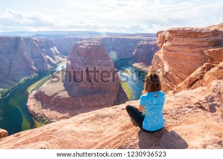 Enjoying the view at the incredible Horseshoe Bend, a horseshoe-shaped meander of the Colorado River located near the town of Page, Arizona. Young woman enjoying view of Horseshoe bend, Arizona. Royalty-Free Stock Photo #1230936523