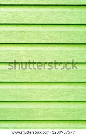 Light green lime wall of the house lined with wooden lining. Vertical green light background with paint and wood texture with straight parallel lines.
