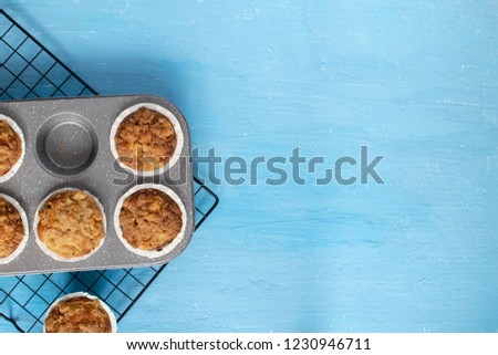 Homemade baking concept - fresh baked muffins on cooling rack, minimal picture, bright blue background, background, top view, copy space.